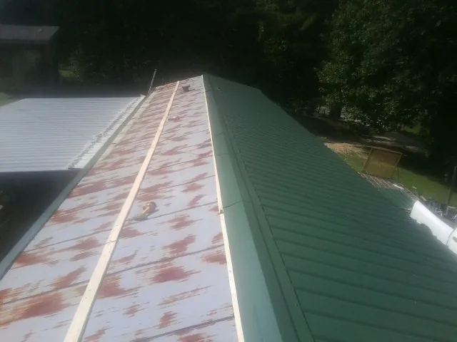 Old rusted panels beside newly installed green metal roofing — Wind Damage Roof Repair by Roofing Brothers in Lake In The Hills