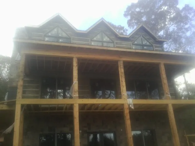 Dormers and porch framing on a large log home under construction — Roof Coating work by our crew in Lake In The Hills