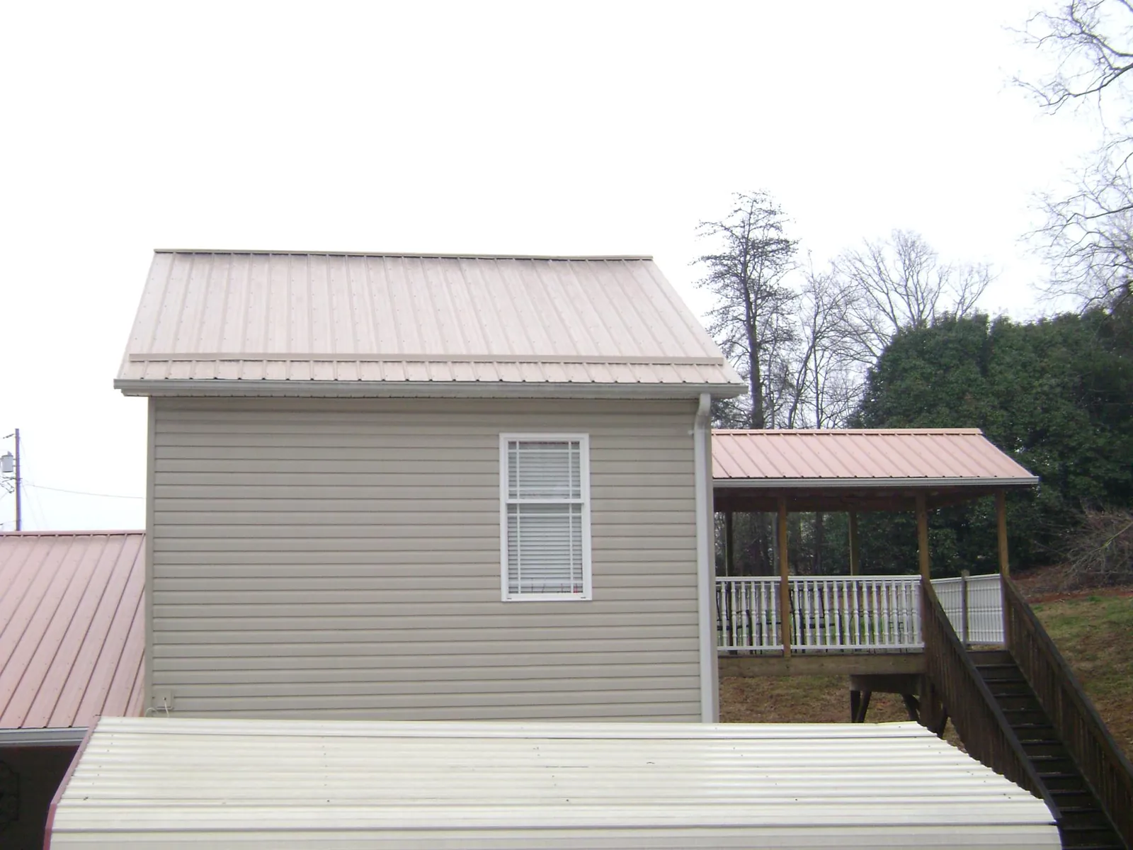 Tan metal roofs on a two story addition and attached porch, from a Roof Replacement job in Lake In The Hills