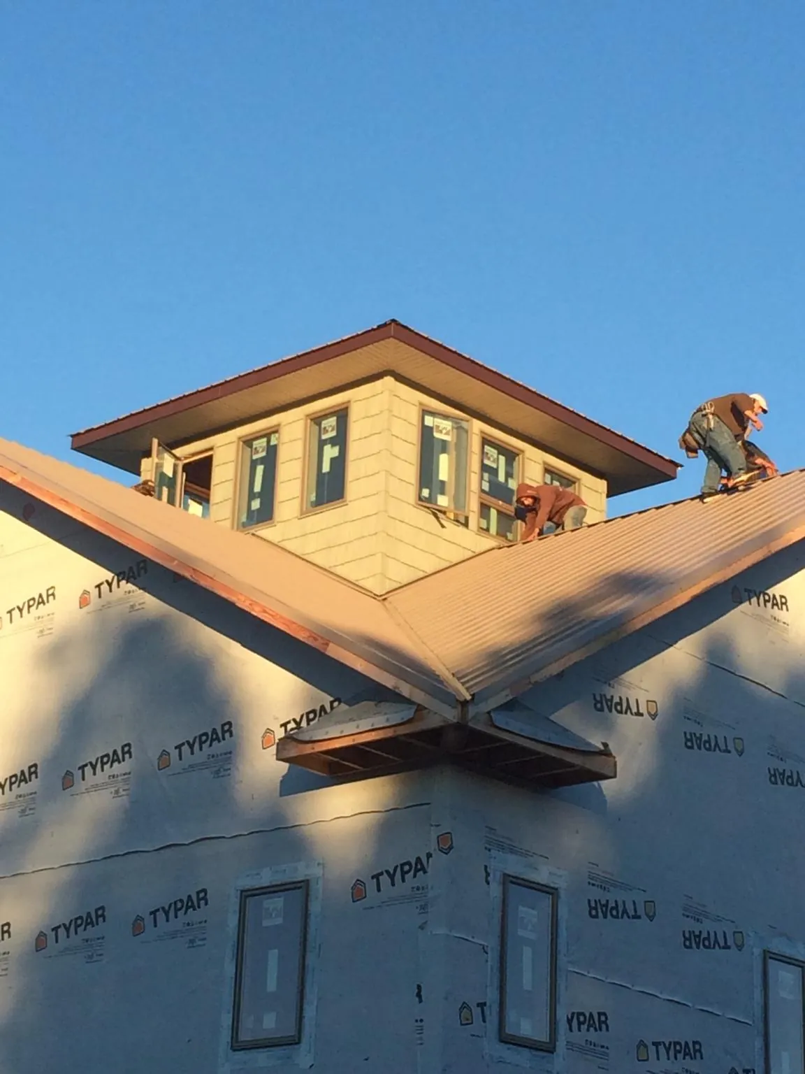 Roofers working around a rooftop cupola on a new metal roof at sunset — Roof Waterproofing in Lake In The Hills by Roofing Brothers